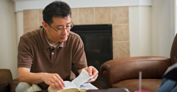 英語の聖書を読むアジア系の男性