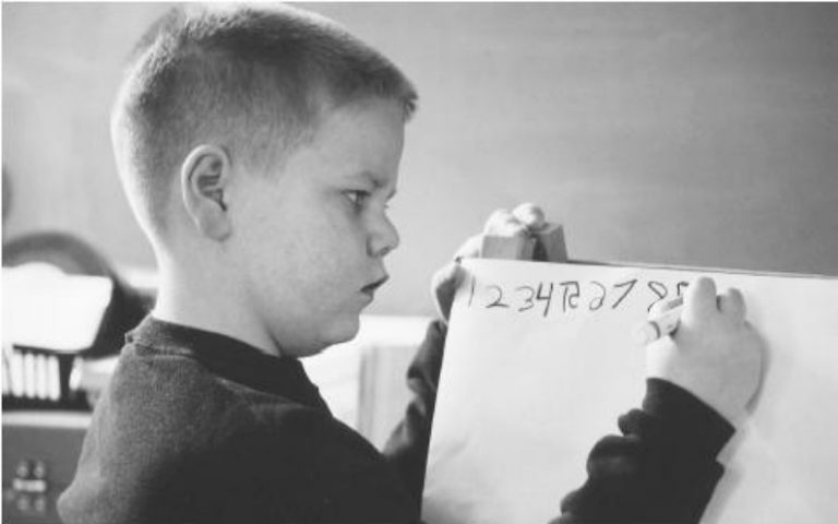 紙に数字を書く少年