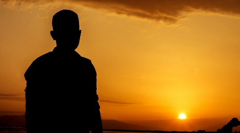 夕陽を見つめ、たそがれる男性のシルエット