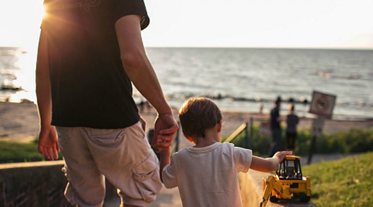 息子の手を握り散歩する父親