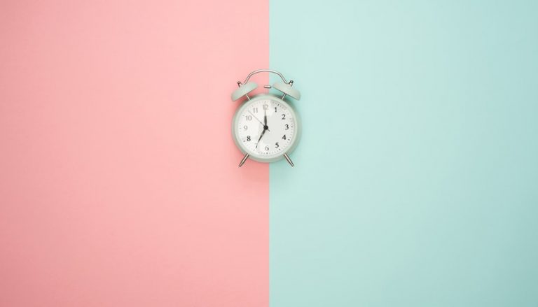 ピンクと緑のバックグラウンドの真ん中にある目覚まし時計
