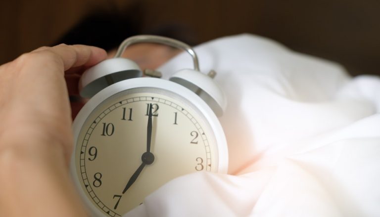 ７時のめざまし時計を抱える
