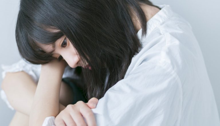 心の葛藤で悩みうずくまっている女性