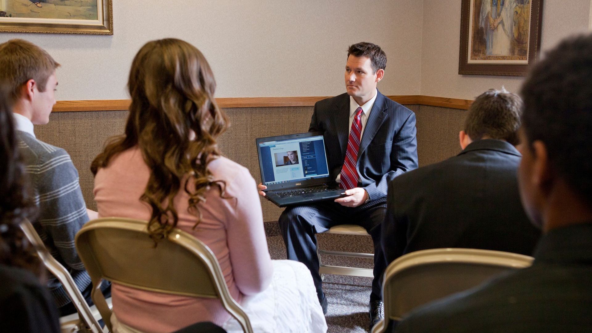 日曜学校の時間にノートパソコンで動画を紹介する教師